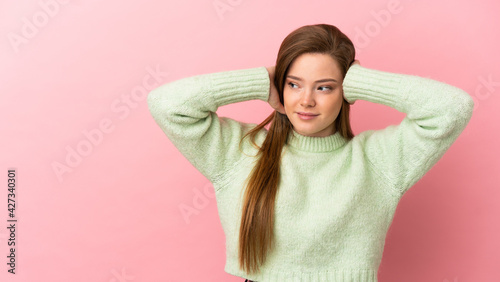 Teenager girl over isolated pink background frustrated and covering ears © luismolinero