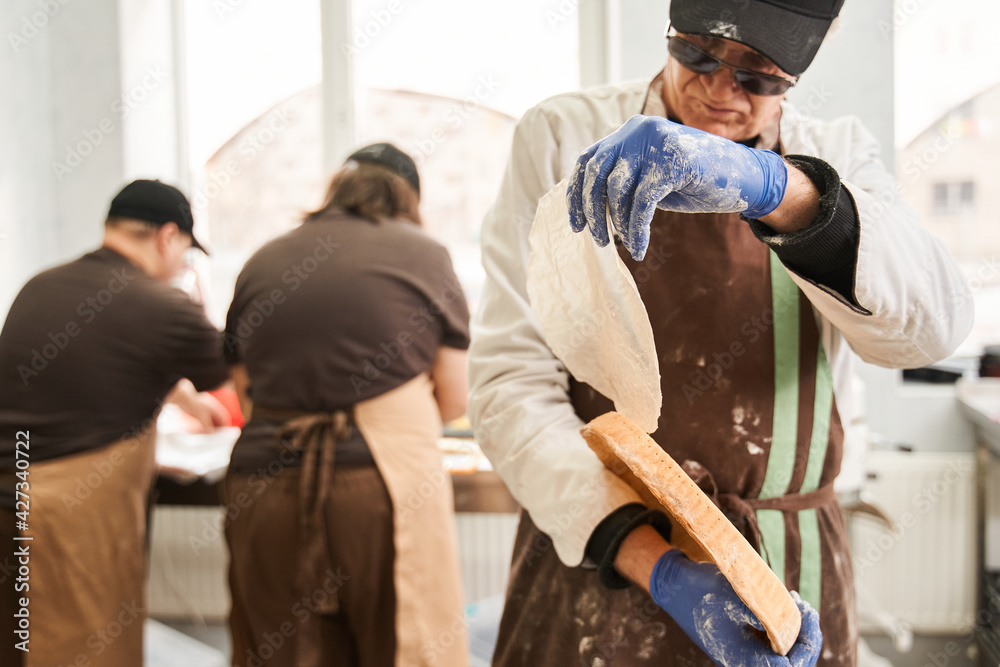 Male chef wearing apron looking at the empty form of the pie Male chef wearing apron looking at the empty form of the pie