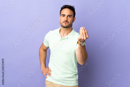 Young handsome man isolated on purple background making Italian gesture