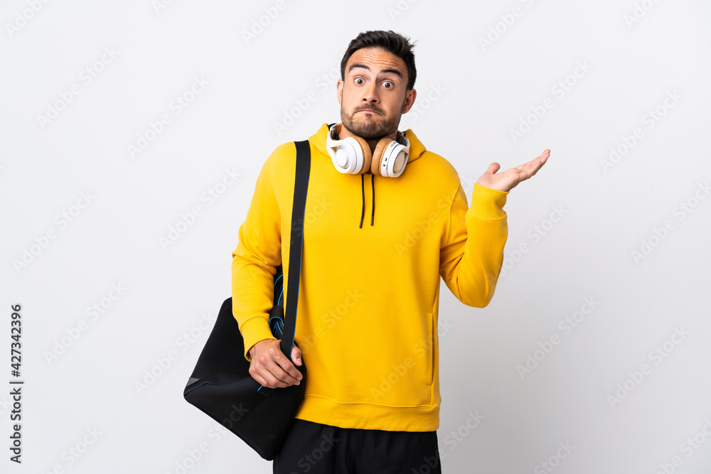 Young sport man with sport bag isolated on white background making doubts gesture