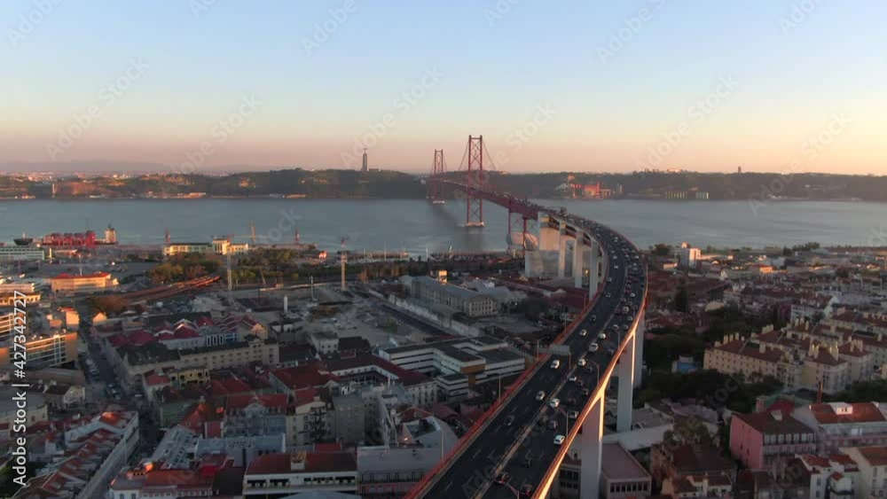 Aerial tilt up shot showing traffic on 25 of April bridge (Portuguese: Ponte 25 de Abril) over the Tagus River at sunset in Lisbon, Portugal. Aerial tilt up shot showing traffic on 25 of April bridge (Portuguese: Ponte 25 de Abril) over the Tagus River at sunset in Lisbon, Portugal.