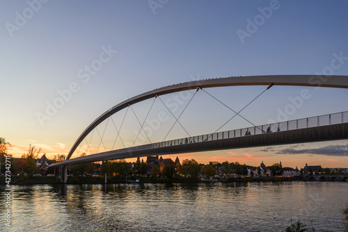 Outdoor scenery on riverside of Meuse river and Hoge Brug, Modern pedestrian bridge, during sunset time and dramatic twilight sky in Maastricht, Netherlands. 