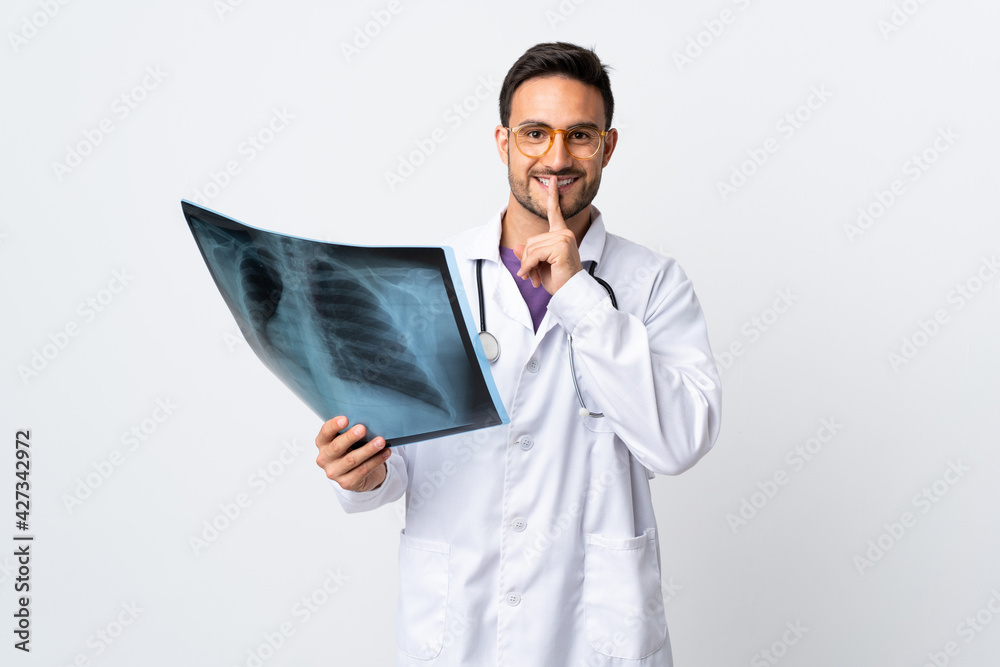 Young doctor man holding a radiography isolated on white background doing silence gesture Young doctor man holding a radiography isolated on white background doing silence gesture