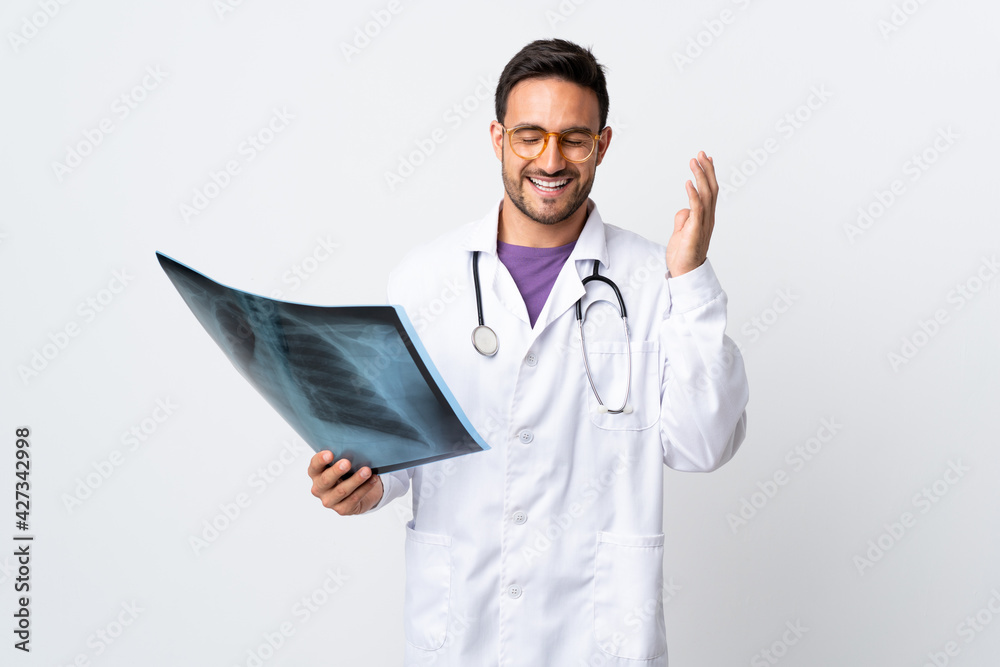 Young doctor man holding a radiography isolated on white background laughing Young doctor man holding a radiography isolated on white background laughing
