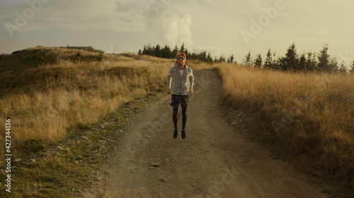 Male runner warming legs before workout. Man jumping on dirty road in mountains © stockbusters