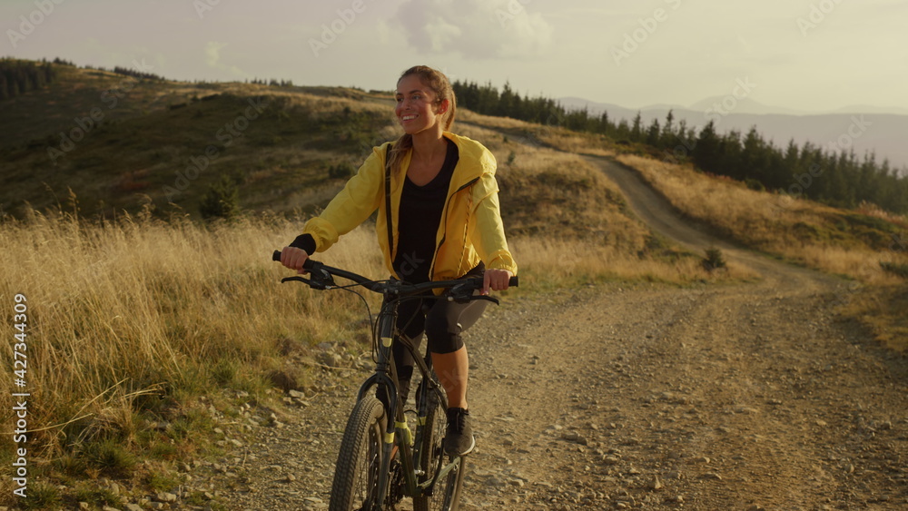 Rider cycling on sport bike in mountains. Smiling woman riding mountain bike 