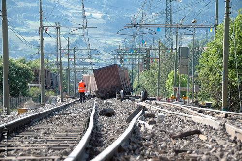 Massive freight train derailed along the tracks. Tracks, freight trolleys, wheels and sleepers damaged after a collision between trains.