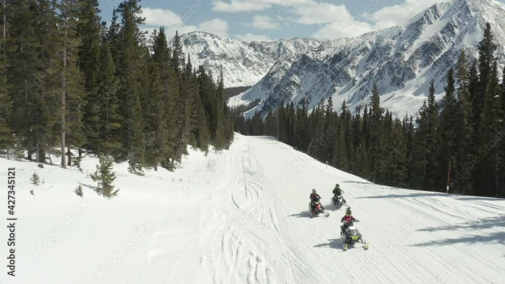 drone shot of snowmobiles traveling across the snow in the mountains drone shot of snowmobiles traveling across the snow in the mountains