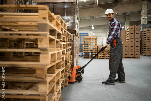 Foto Caucasian warehouse worker lifting weight with manual pallet jack
