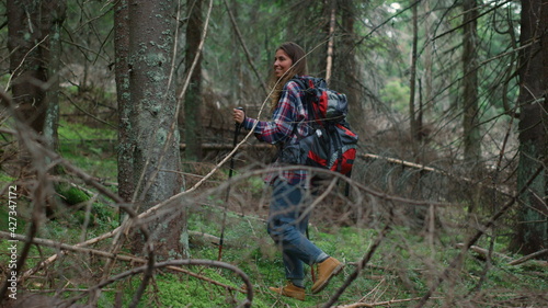 Woman with backpack trekking in woods. Smiling lady walking in fairytale forest