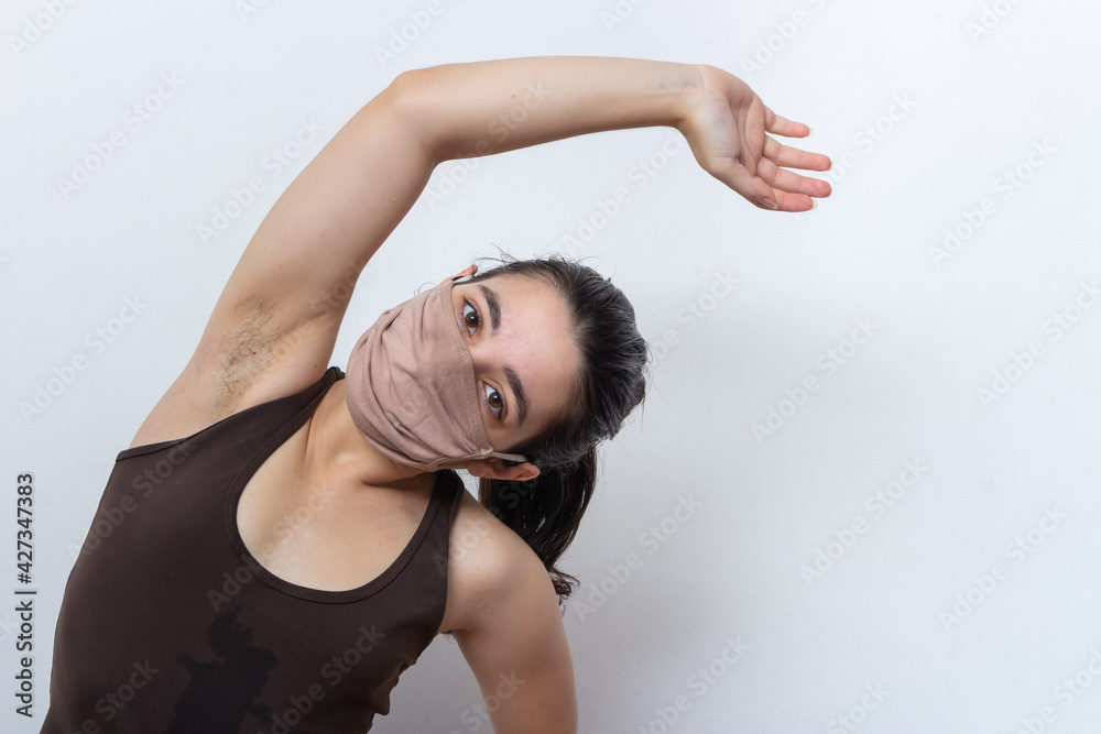 Brown tank top woman on white background with mask tied hair exercising Brown tank top woman on white background with mask tied hair exercising