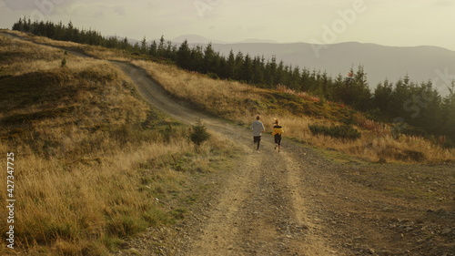 Sportsman and sportswoman jogging in mountains. Young couple exercising outdoor