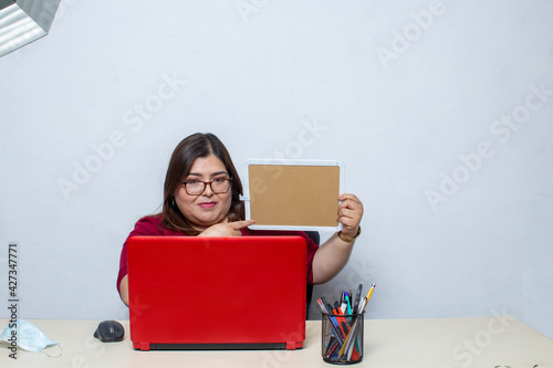 Foto Young fat woman showing and pointing at empty blackboard on video call on video call