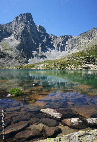 Wild mountain lake on a sunny summer day, rocky bottom