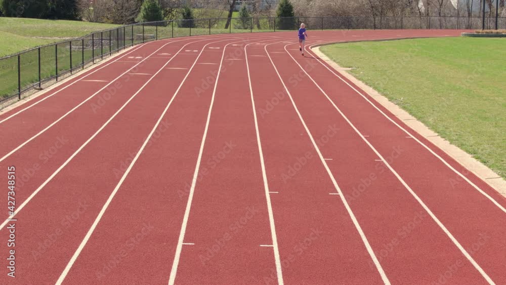Teen girl runs track towards camera in slow motion on a pretty day. Teen girl runs track towards camera in slow motion on a pretty day.