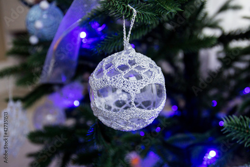 Knitted Christmas toys, handmade. Christmas tree toy made of threads. Blue light.
