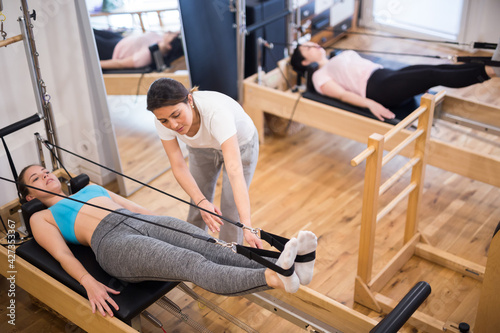 Girl assisting woman during pilates