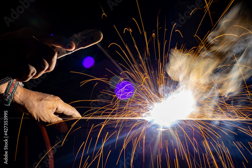 Iron welding close-up, sparks do not wear gloves. Welding sparks and fumes It can be dangerous to health.