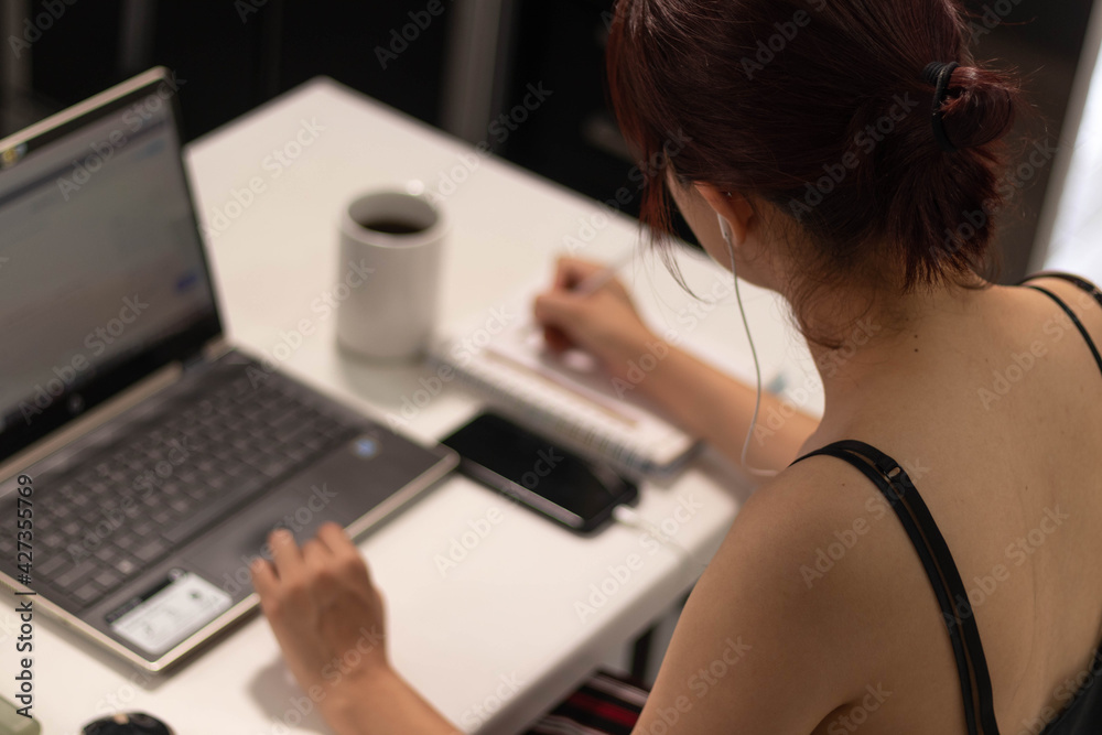 woman working on laptop and writing woman working on laptop and writing