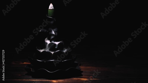 Incense cones holder. Ceramic backflow incense burner in the form of lotus flower. Dark mystic concept.