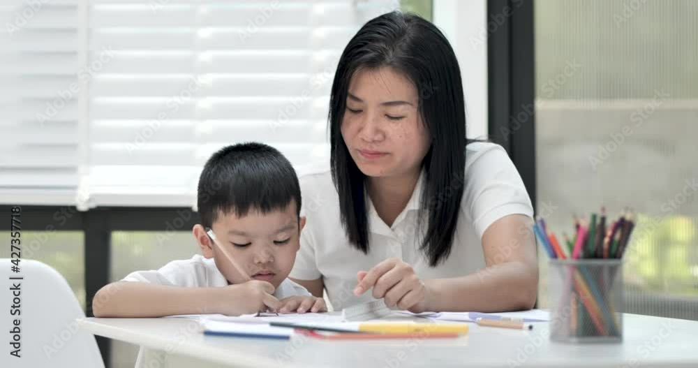 Mother and son doing homework at home, Mother is teaching son to draw pictures, Children homework. Young boy. doing homework on the terrace at home. Happy mood. Back to school concept. Mother and son doing homework at home, Mother is teaching son to draw pictures, Children homework. Young boy. doing homework on the terrace at home. Happy mood. Back to school concept.
