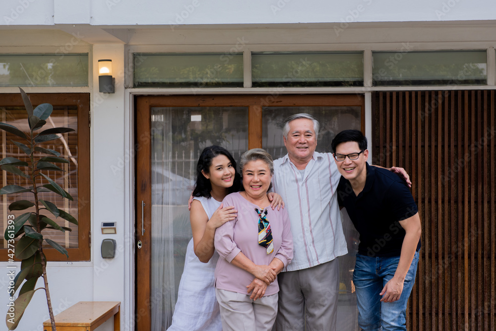 Two-generation family standing in front of the house together with love. Adult couple visit to senior parents spending time relax and having fun on weekend vacation together at home with happiness. Two-generation family standing in front of the house together with love. Adult couple visit to senior parents spending time relax and having fun on weekend vacation together at home with happiness.