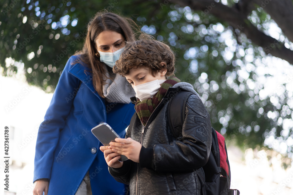 Fototapeta premium cute boy showing how to use the smartphone to his mom. Children addicted to mobile cell phone and the internet concept in new normal coronavirus time.