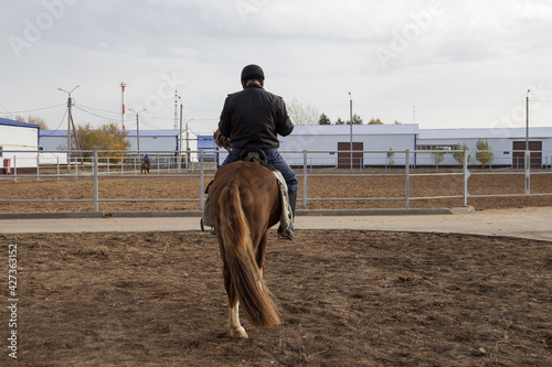 Mounted police rider on horseback, rear view. Mounted police in Kazakhstan. A rider in a police uniform riding on an equestrian hippodrome