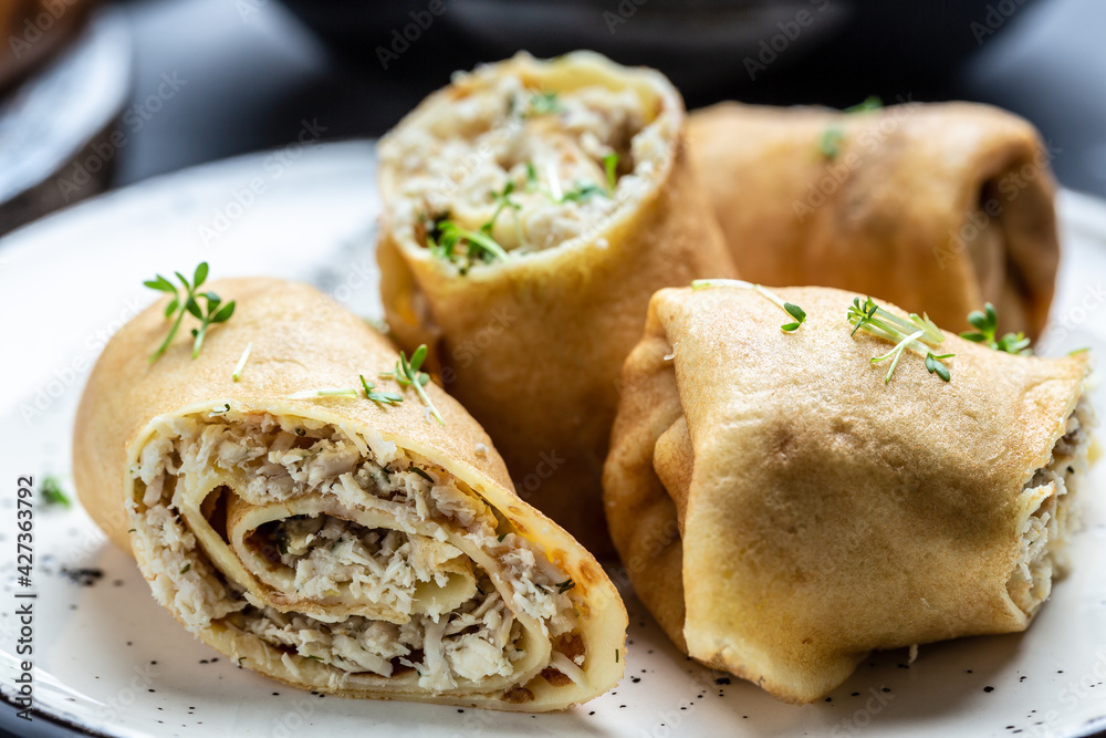 Delicious crepes rolls with chicken meat and cheese. Traditional Russian Shrovetide Maslenitsa festival meal. Food recipe background. Close up Delicious crepes rolls with chicken meat and cheese. Traditional Russian Shrovetide Maslenitsa festival meal. Food recipe background. Close up