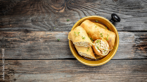 Savory crepe rolls with ground chicken meat on a wooden table, Long banner format, top view