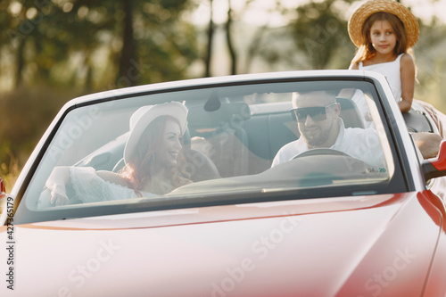 Family in a cabriolet convertible car at the sunset