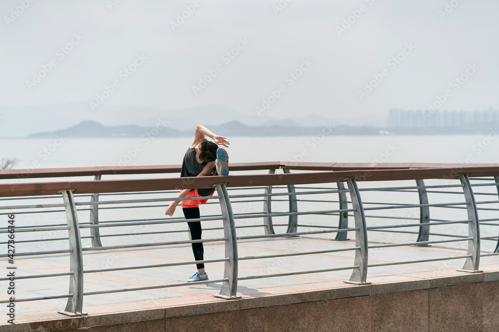 young asian woman in sportswear stretching legs outdoors