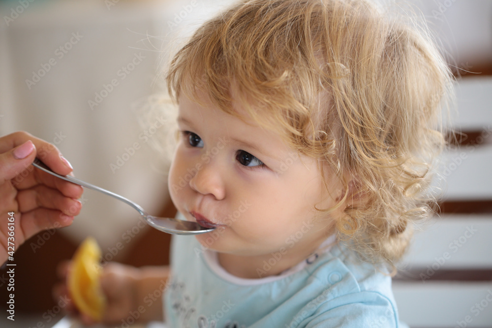 Mother giving healthy food to her adorable child at home. Feeding kids. Mother giving healthy food to her adorable child at home. Feeding kids.