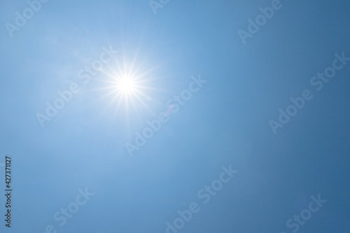 Shining sun on clear blue sky. lens flare of sunlight on blue sky background. Bright sun on blue sky.