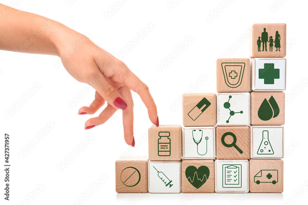 Stacked cubes and female hand on white background. Health care insurance concept Stacked cubes and female hand on white background. Health care insurance concept