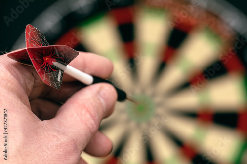 Man hand is holding dart and aiming at target. Achieving goal. game of darts. Aspiration, determination, perseverance. Selective focus