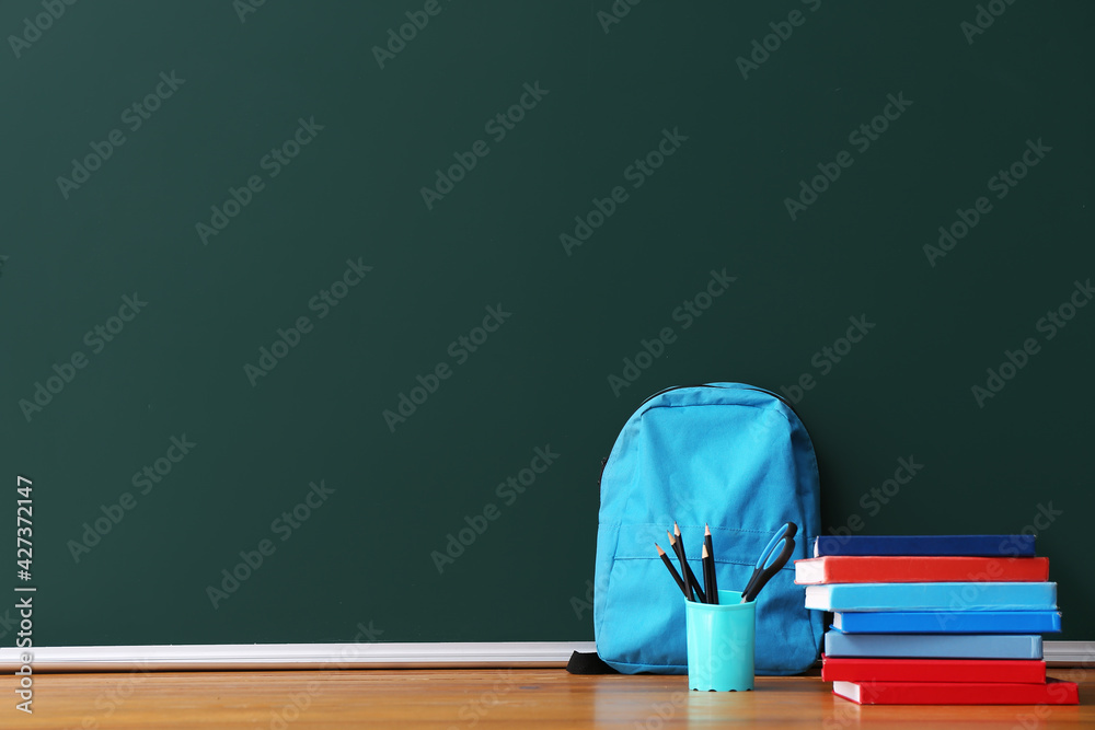 Stack of books with pencils and backpack on color background Stack of books with pencils and backpack on color background