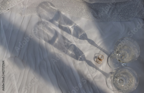 shadows from wedding glasses and wedding rings on a white background