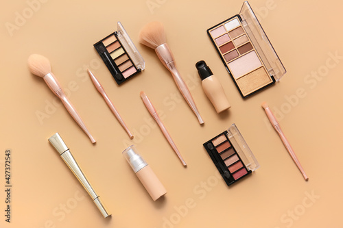 Stylish makeup brushes and cosmetics on color background