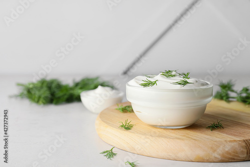 Tableau sur toile Bowl of tasty sour cream and herbs on grey background