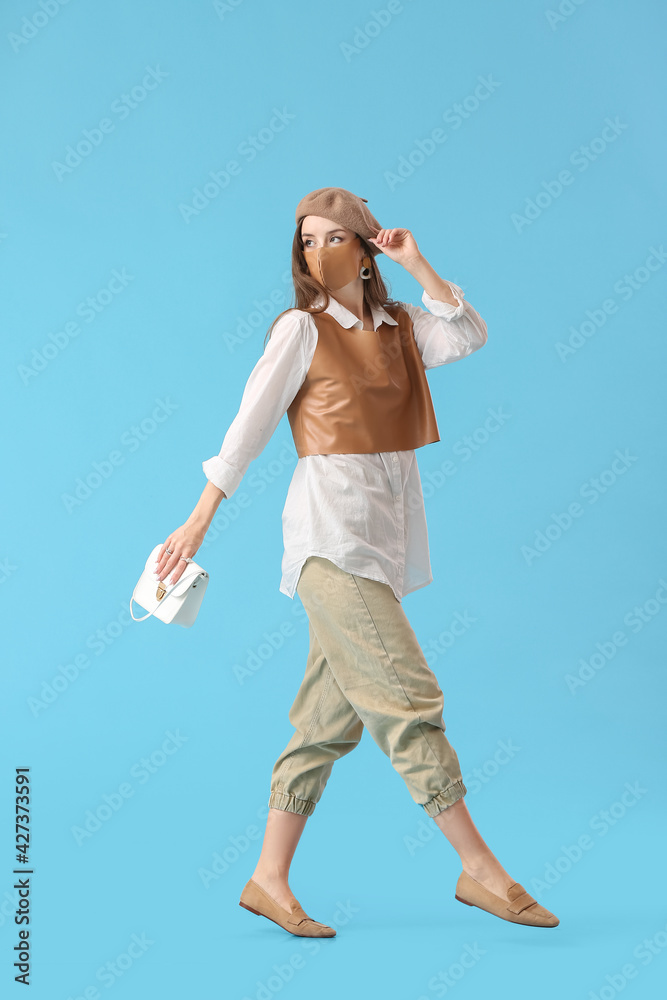 Fashionable young woman wearing mask on color background Fashionable young woman wearing mask on color background