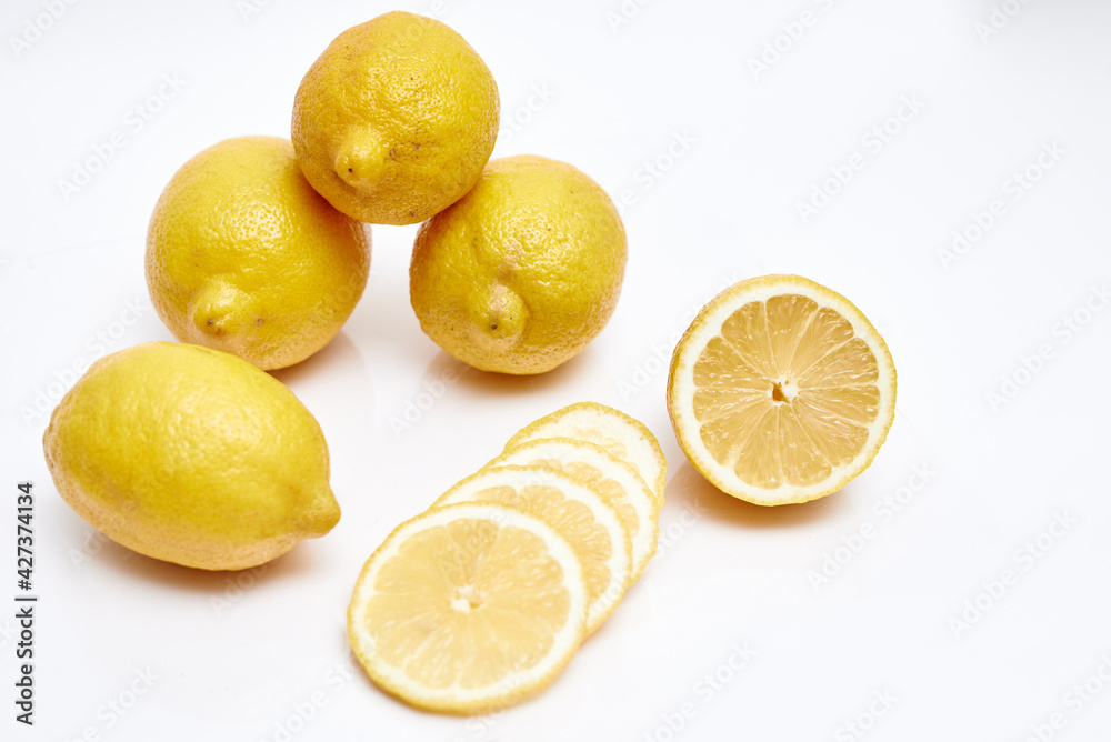 ripe lemons and lemon slices on white background