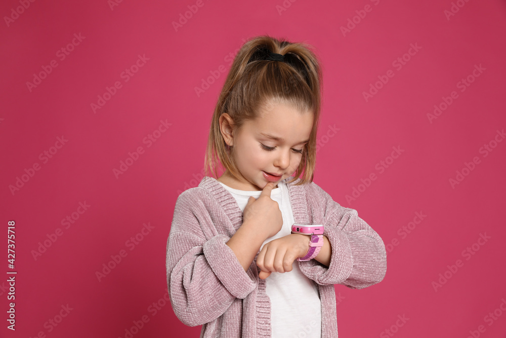 Little girl with smart watch on pink background Little girl with smart watch on pink background
