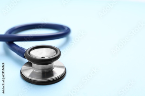 Stethoscope on light blue background, closeup. Space for text
