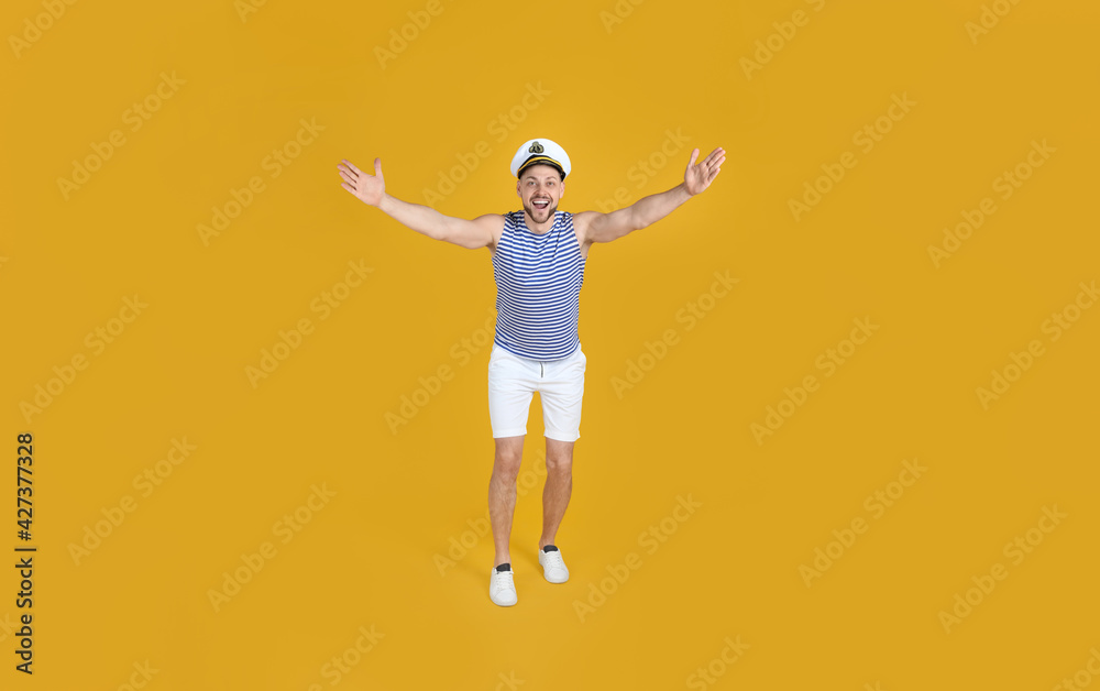 Happy sailor wearing cap on yellow background