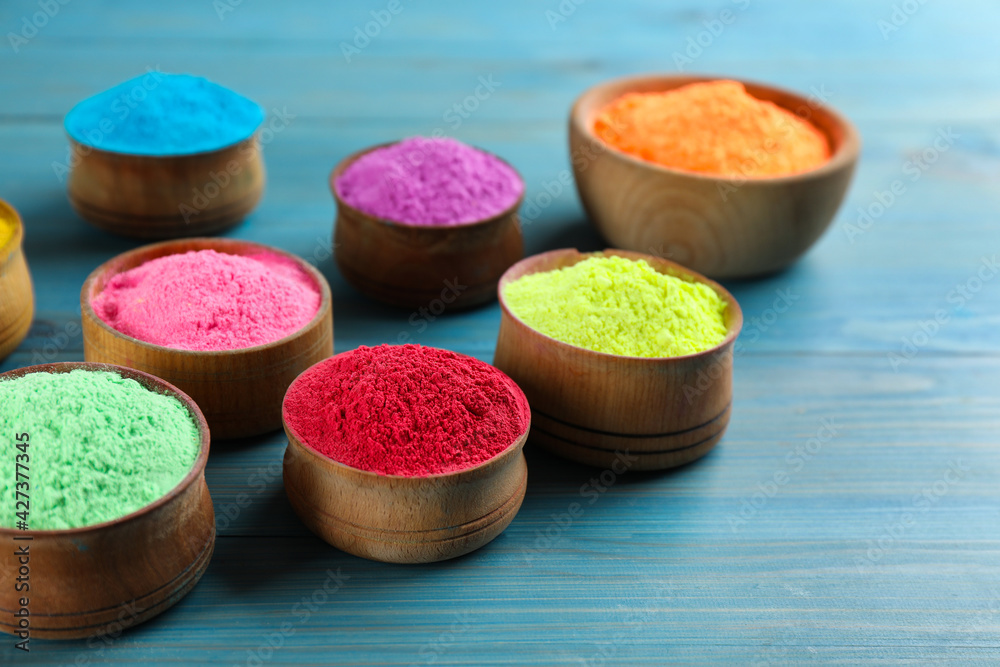 Colorful powder dyes on light blue wooden background, closeup. Holi festival Colorful powder dyes on light blue wooden background, closeup. Holi festival