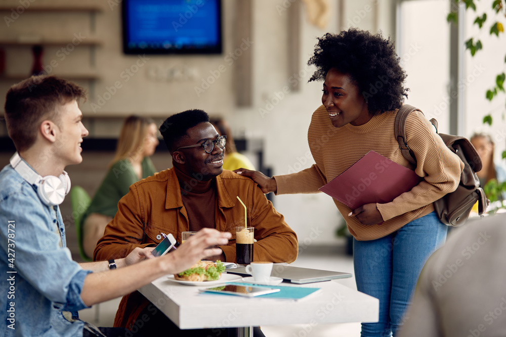 Obraz premium Multi-ethnic group of college friends talking on break in cafeteria.