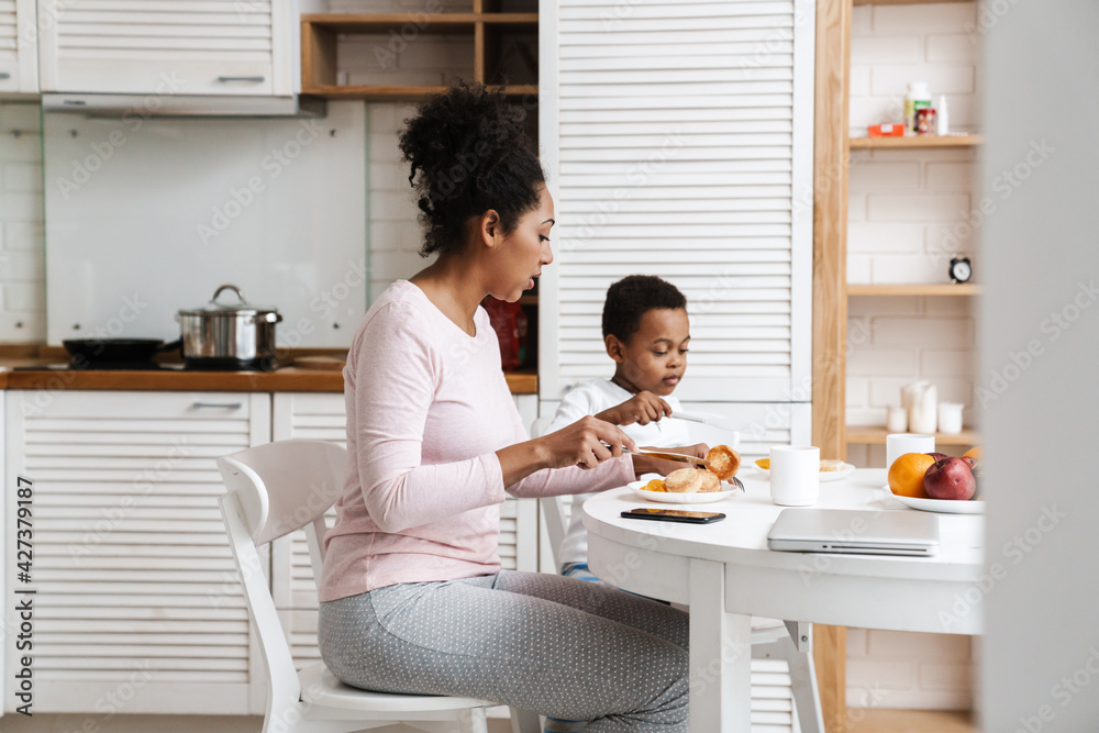 Black mother and son having breakfast together while sitting at home Black mother and son having breakfast together while sitting at home