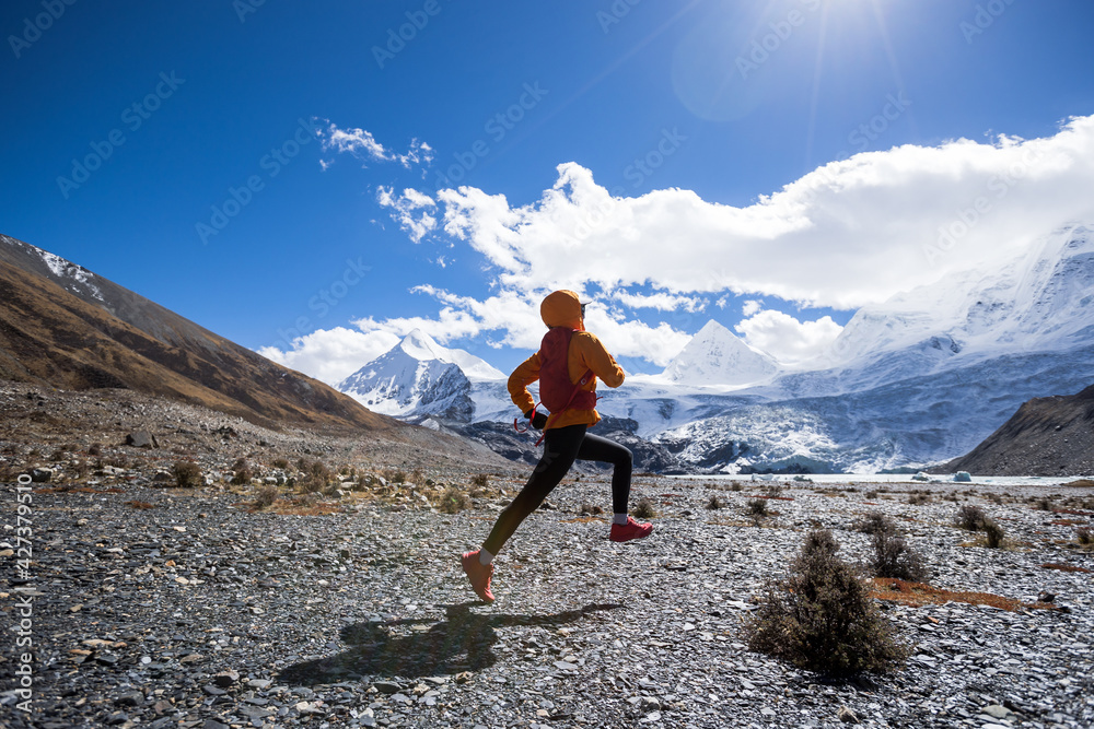 Woman trail runner cross country running in high altitude winter nature