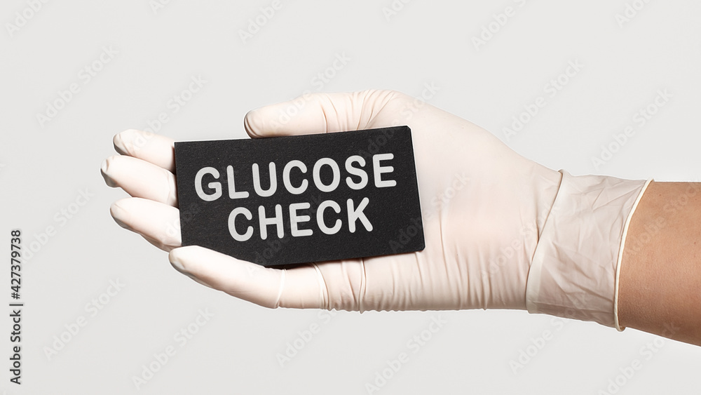 Closeup of the hand in a white sterile glove holding a card with words - glucose check Closeup of the hand in a white sterile glove holding a card with words - glucose check